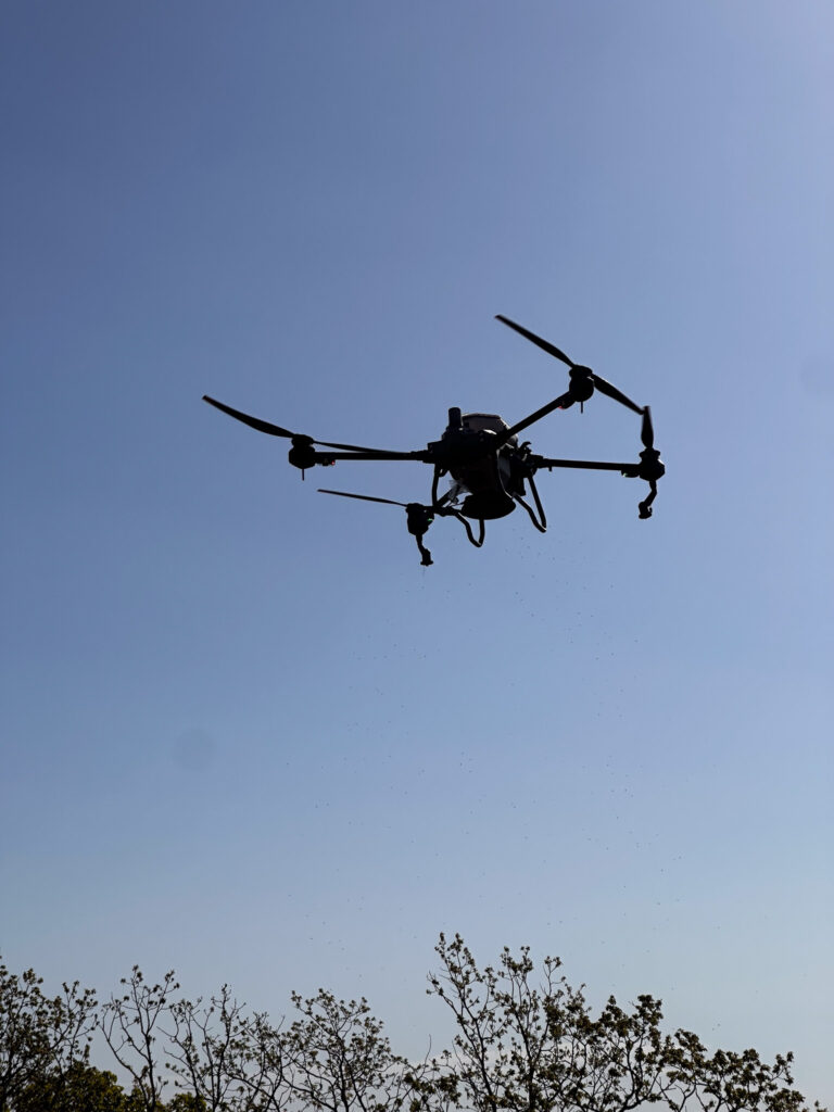 Doss Drone Services DJI T40 large agricultural spray drone in flight over East Texas during herbicide spraying operation