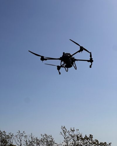 Doss Drone Services DJI T40 large agricultural spray drone in flight over East Texas during herbicide spraying operation