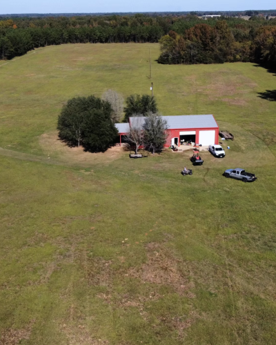 Aerial drone photo of East Texas farm with red barn and surrounding pasture land